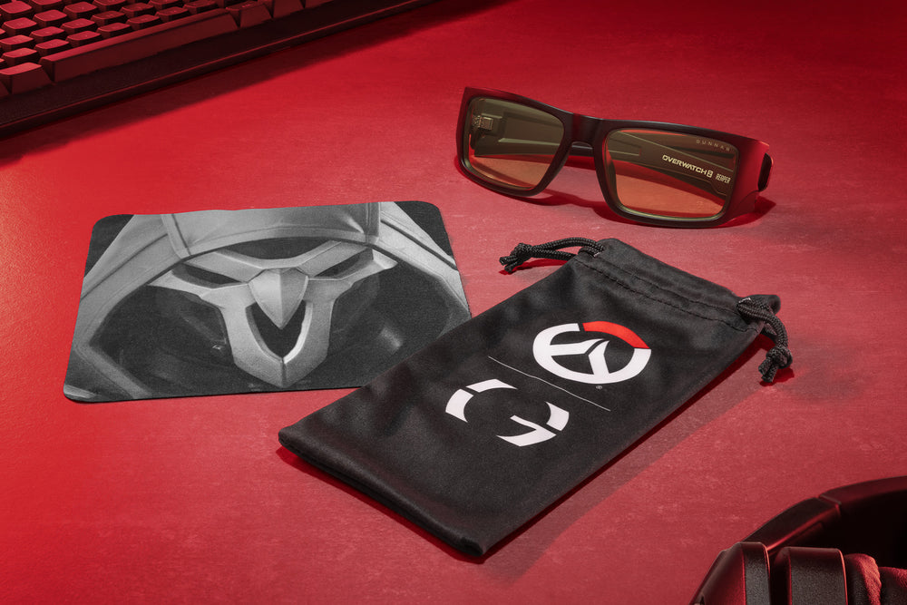 GUNNAR Overwatch Reaper eyeglasses and themed microfiber accessories on red background